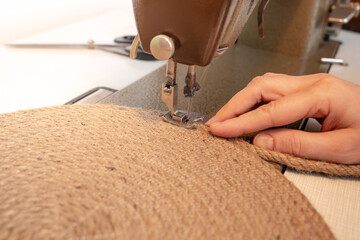 Hand made jute rope placemat at a sewing machine, soft focus close up with motion blur