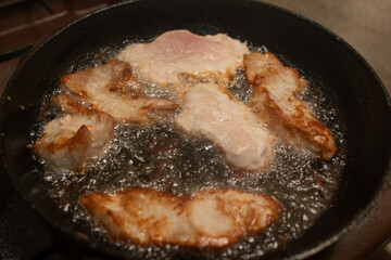 Pork meat boiling in oil, soft focus close up