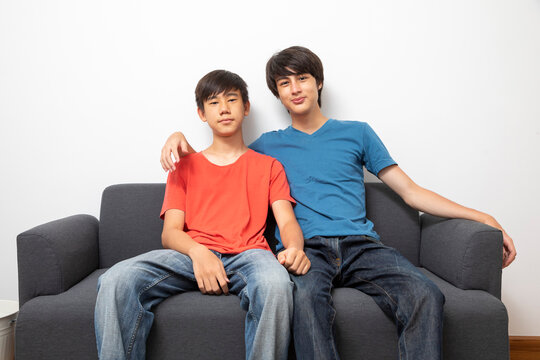 Two boys sitting on sofa and watching TV together. Isolated on white background