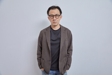 Obraz premium Handsome Asian businessman in suit with eyeglass smile and look at camera on grey background.