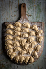 Raw dumplings varenik - traditional Ukrainian food - on wooden board close up. Food photography