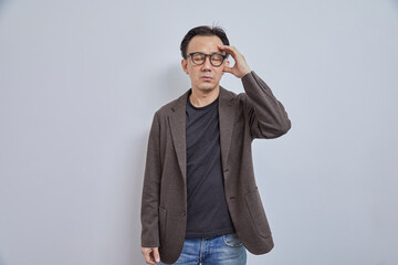 Portrait of stressed Japanese businessman in suit having headache on grey background.