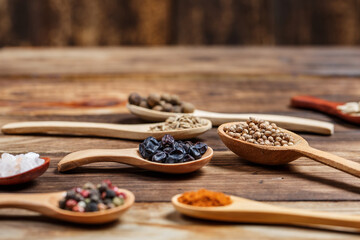 Many different spices in wooden spoons on a wooden background, background with spices, spices in...