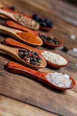 Many different spices in wooden spoons on a wooden background, background with spices, spices in spoons