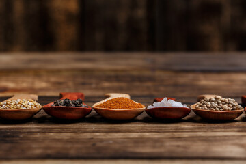 Many different spices in wooden spoons on a wooden background, background with spices, spices in...