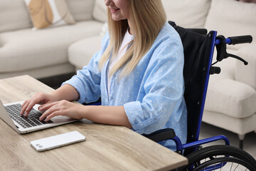 Woman in wheelchair using laptop at home, closeup