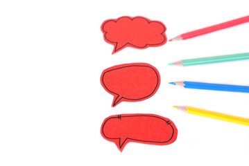 Three red bubble speech paper cards and colored pencils on white background. Concept, teaching aid....