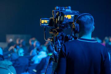 Back view of male videographer recording global seminar in illuminated conference hall
