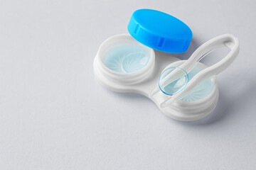 Contact lenses with container and tweezer on gray background