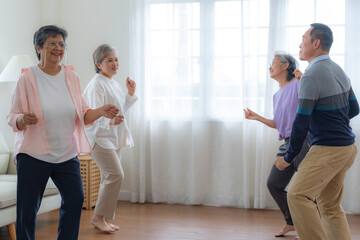 Asian Older male and females people dance with their partners on a dancing floor in living space. Happy older couple performing get exercise. Joyful carefree retired senior friends enjoying relaxation