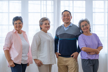 group of asian senior people standing with smart confidence. older people are listening and enjoy meeting focus group at living room. Joyful carefree retired senior friends enjoying relaxation.