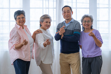 Fototapeta na wymiar group of asian senior people standing with smart confidence. older people are listening and enjoy meeting focus group at living room. Joyful carefree retired senior friends enjoying relaxation.