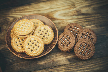 Chocolate and vanilla round cookies on a wooden table with a cup of coffee, round cookies on the...