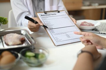 Cropped shot of nutritionist showing example of weekly menu during consultation with patient in clinic