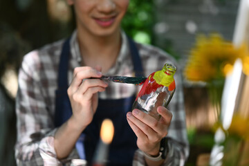 Happy Asian man painting on a glass jar with a brush in workshop. Indoors leisure activity concept