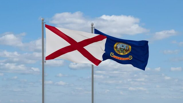 Idaho and Alabama US state flags waving together on cloudy sky, endless seamless loop