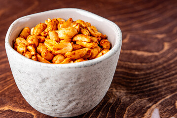 Roasted peanuts and salt in a bowl on a wooden background