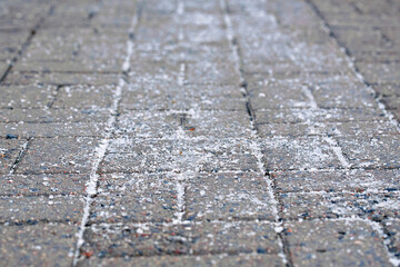 Salt granules on paving slab and asphalt roads for deicing. Salt crystals on pedestrian paving...