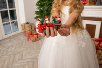 Hands of a child holding a gift, A wooden train toy is carrying New Year's gifts. Cozy home New Year atmosphere.wooden vintage train