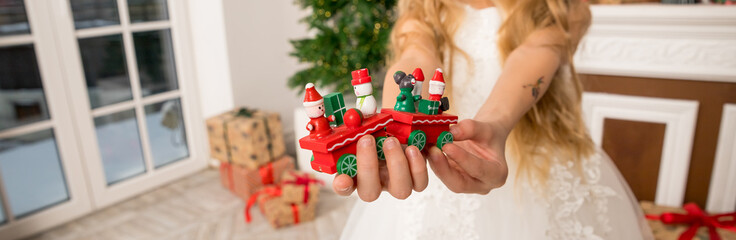 Hands of a child holding a gift, A wooden train toy is carrying New Year's gifts. Cozy home New Year atmosphere.wooden vintage train. web banner