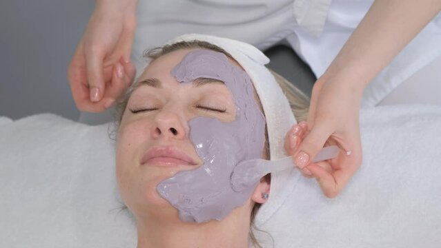  A cosmetologist applies a mask to the patient's face, professional cleaning, skin peeling.