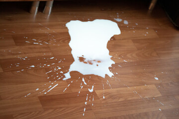 Spilled milk on the floor. White spot of liquid with splashes. Healthy beverage dropped by accident