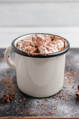 Homemade spicy hot chocolate drink with white marshmallows in enamel cup on wooden table
