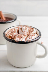 Homemade spicy hot chocolate drink with white marshmallows in enamel cup on wooden table