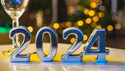 The number 2024 made of silver metal, blurred background of a New Year's Eve party at night