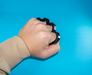 Black Steel brass knuckles blue background hooligan fight, fighting without rules, street banditry,...