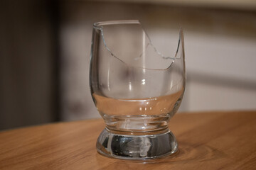 Broken transparent drinking glass on the table. Sharp dangerous pieces in the kitchen.