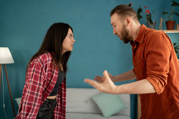 Domestic violence and emotional abuse, stressed woman and aggressive angry man screaming at each other in the living room.