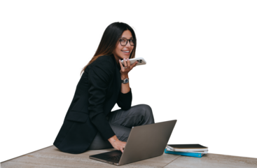 Cheerful American young businesswoman in glasses and black jacket sitting against transparent background, notebook, recording audio message looks at camera happily,