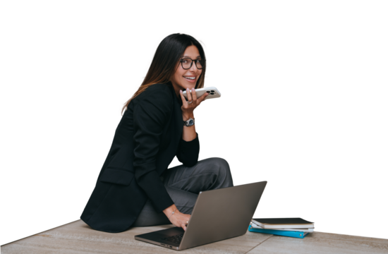 Cheerful American young businesswoman in glasses and black jacket sitting against transparent background, notebook, recording audio message looks at camera happily,
