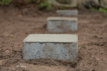 Une série de plots en béton alignés sur un sol pour supporter la structure d'une installation de...