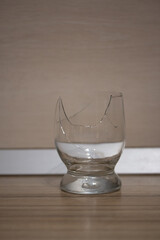 Broken transparent drinking glass in the kitchen. Sharp dangerous pieces. Vertical picture