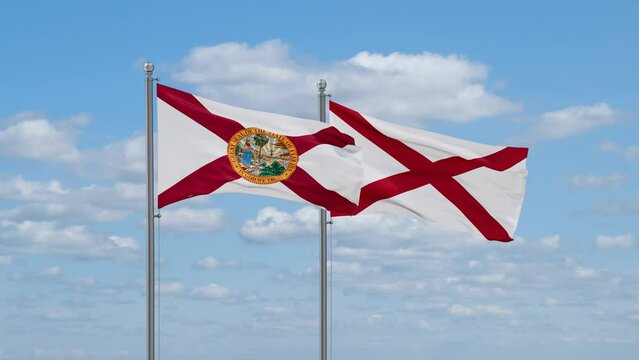Alabama and Florida US state flags waving together on cloudy sky, endless seamless loop