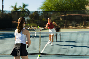 Caucasian teen girl seen from behind playing a tennis match