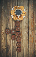 Chocolate and vanilla round cookies on a wooden table with a cup of coffee, round cookies on the table