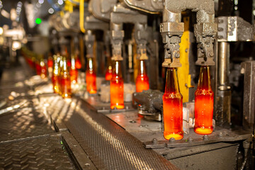 Glass factory, production of glass containers. Molten glass is blown into molds. Robotics in...