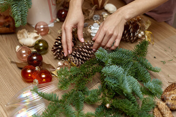 Woman making Christmas arrangement with fir branches and pine cones. craft handmade decor.