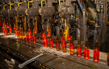 Glass factory, production of glass containers. Molten glass is blown into molds. Robotics in industry. Modern technologies, robotic machines produce products. Technological work at the plant.