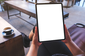 Mockup image of a woman holding digital tablet with blank white desktop screen in cafe