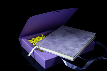 Best gift for men. Man gift concept. Purple notebook with purple gift box on black background. Copy space. Valentine's day, wedding, birthday and special occasion gift concept. Copy space for text.