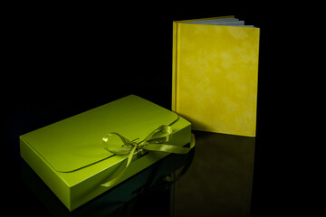 Best gift for men. Man gift concept. Yellow notebook with green gift box on black background. Copy space. Valentine's day, wedding, birthday and special occasion gift concept. Copy space for text.