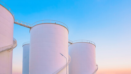 Group of white storage fuel tanks in petrochemical industrial area against beautiful dusk sky...