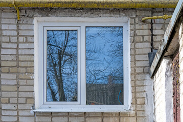 White PVC double casement window with blue sky reflection. Brick wall