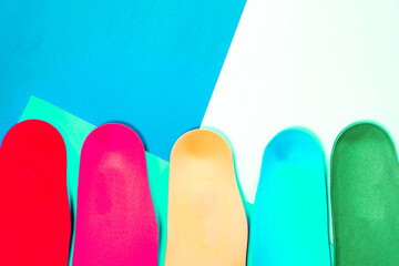 Orthopedic insoles for shoes on a colour background. Foot care