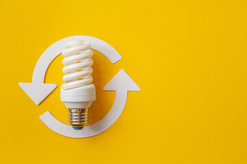 Energy saving light bulb and recycle arrows. Economical consumption of electricity. Orange background . The concept of nature conservation and renewable energy sources with place for text