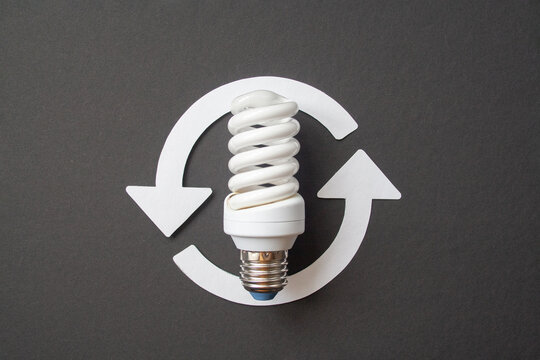 Energy saving light bulb and recycle arrows. Economical consumption of electricity. Black background . The concept of nature conservation and renewable energy sources